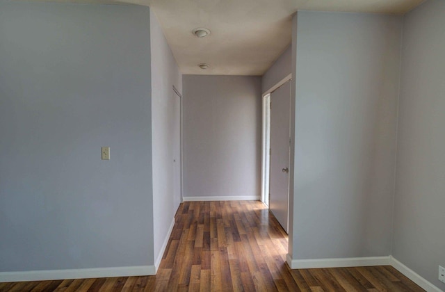 corridor with dark wood-type flooring and baseboards