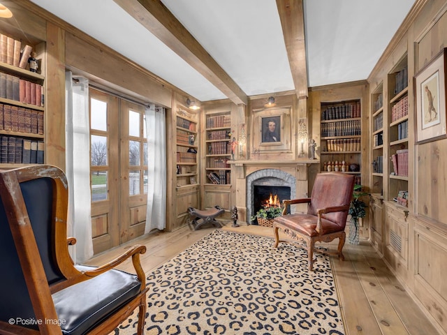 living area featuring french doors, built in features, beam ceiling, and light hardwood / wood-style flooring