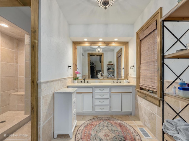 bathroom featuring vanity, tiled shower, and tile walls