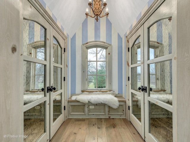 unfurnished room featuring vaulted ceiling, light hardwood / wood-style floors, french doors, and a chandelier