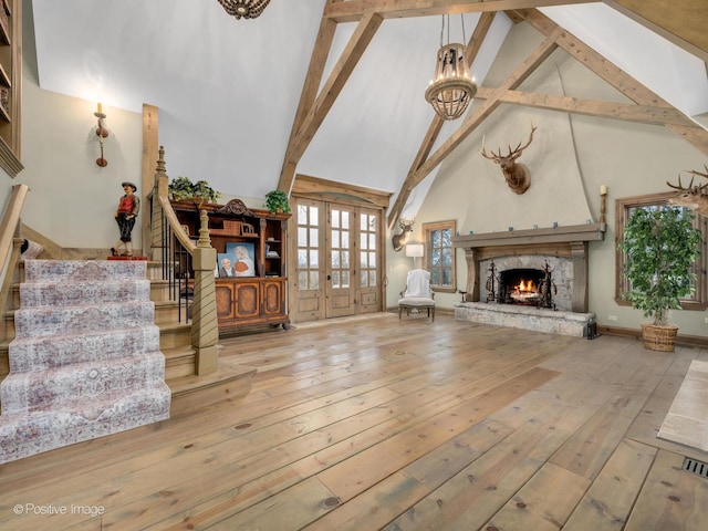 unfurnished living room featuring a stone fireplace, high vaulted ceiling, light wood-type flooring, a chandelier, and beam ceiling