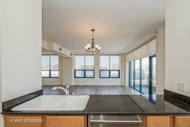 kitchen with sink, decorative light fixtures, dark stone countertops, dishwasher, and a notable chandelier