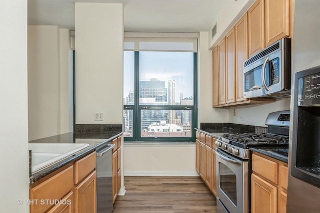 kitchen with dark stone countertops, sink, hardwood / wood-style flooring, and appliances with stainless steel finishes