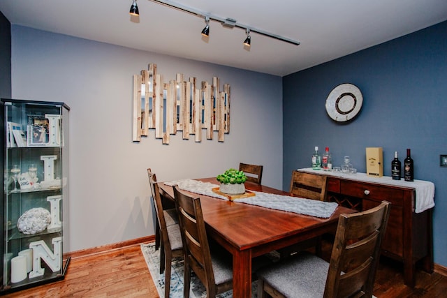 dining space with hardwood / wood-style floors and rail lighting