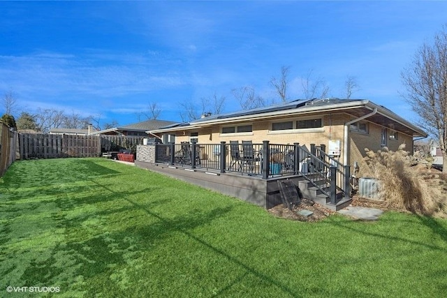 rear view of house with a lawn, solar panels, and a deck