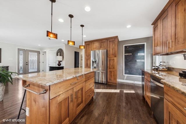 kitchen featuring a kitchen island, appliances with stainless steel finishes, a breakfast bar, pendant lighting, and light stone counters