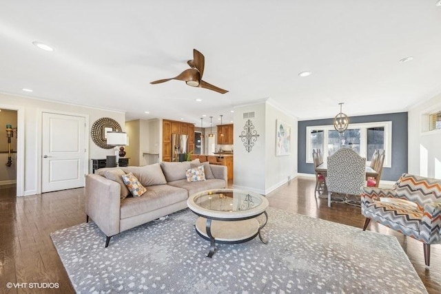 living room with ceiling fan with notable chandelier, ornamental molding, and dark hardwood / wood-style floors