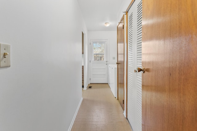 corridor with visible vents, baseboards, light floors, and washing machine and clothes dryer