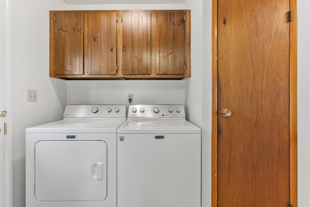 clothes washing area with washing machine and dryer and cabinet space