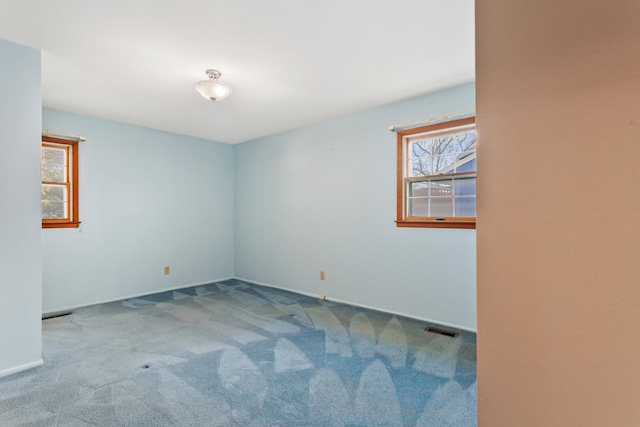 carpeted empty room featuring a healthy amount of sunlight and visible vents