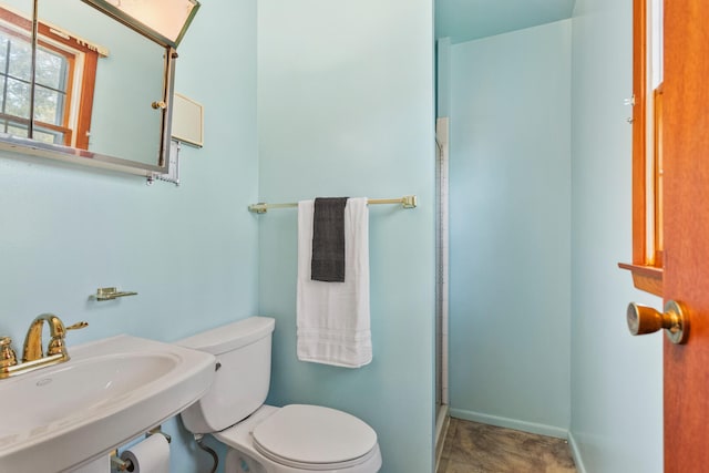 full bathroom featuring a shower with shower door, toilet, baseboards, and a sink