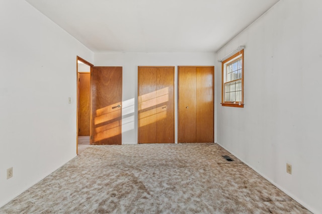 unfurnished bedroom with two closets and carpet