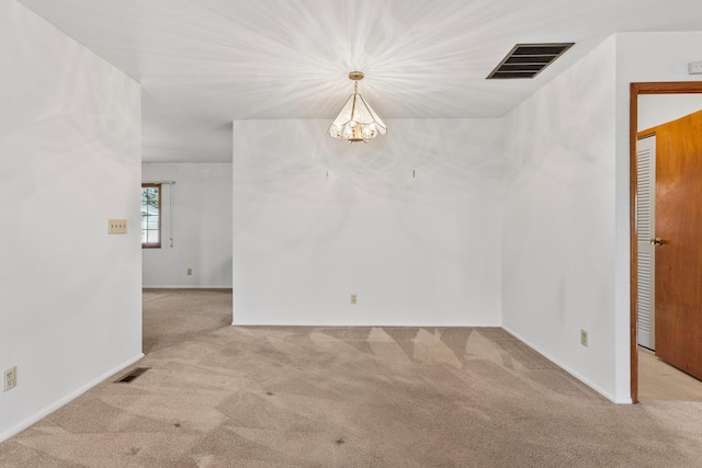 carpeted spare room with visible vents and a chandelier