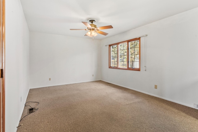 carpeted spare room featuring baseboards and ceiling fan