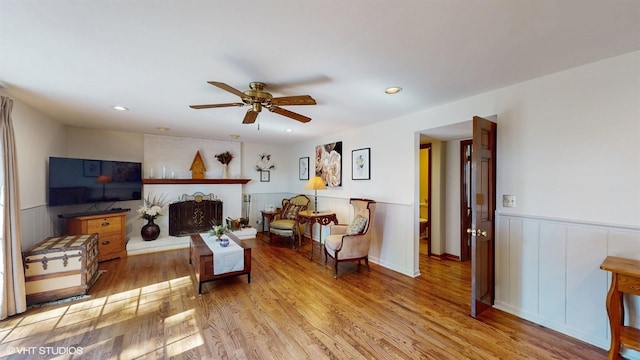 living area with ceiling fan, recessed lighting, wood finished floors, and wainscoting