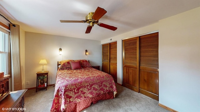 carpeted bedroom featuring baseboards, two closets, and ceiling fan