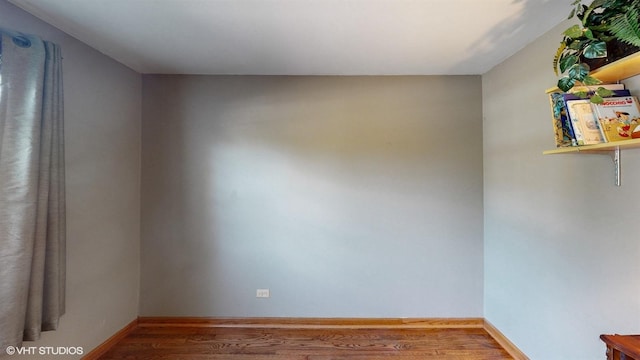 spare room featuring wood finished floors and baseboards