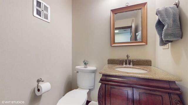 bathroom featuring vanity, toilet, and visible vents