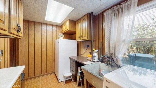 laundry room featuring a sink, cabinet space, wooden walls, and light tile patterned flooring