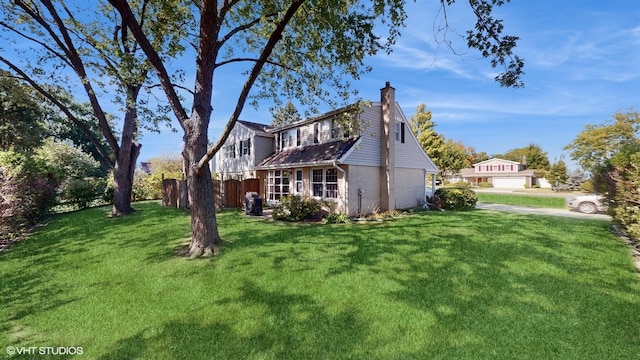 exterior space featuring brick siding, a chimney, a yard, and fence