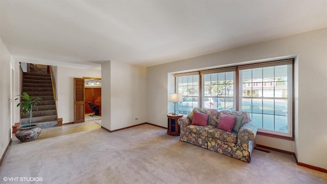 living area with carpet flooring, baseboards, and stairs