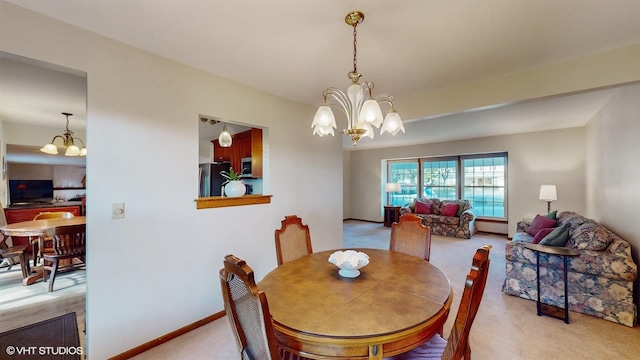 dining area with a chandelier, baseboards, and carpet