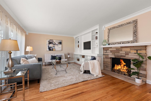 living room featuring hardwood / wood-style flooring, a stone fireplace, ornamental molding, and built in shelves