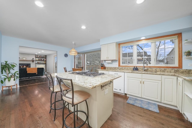 kitchen featuring sink, dishwasher, white cabinetry, a kitchen island, and stainless steel gas stovetop