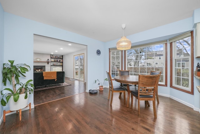 dining space featuring dark wood-type flooring, a fireplace, and built in shelves