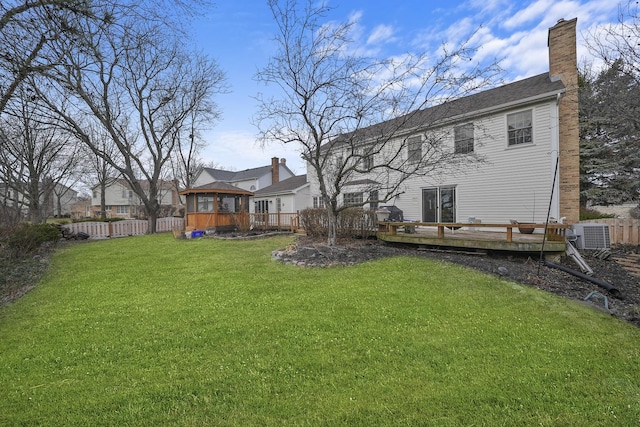 back of property with a wooden deck, a sunroom, a yard, and central AC