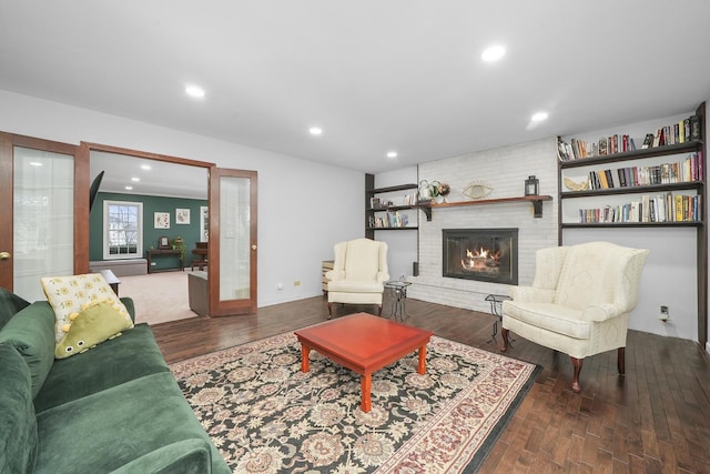 living room featuring a brick fireplace, dark wood-type flooring, and french doors