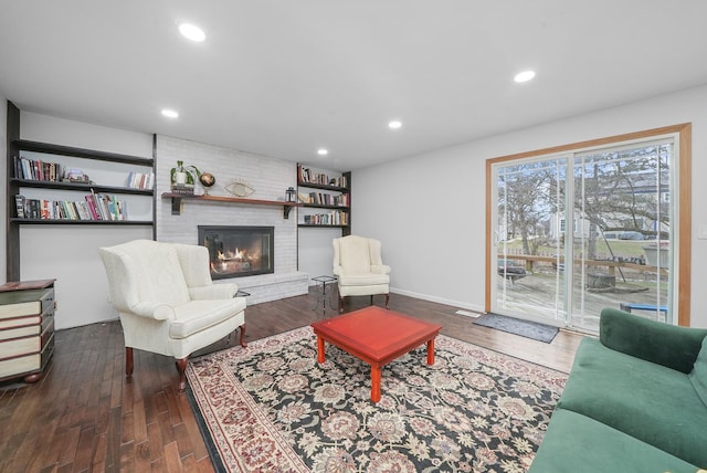 living room with a brick fireplace and dark hardwood / wood-style flooring