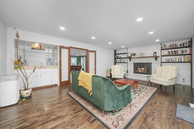 living room featuring sink, dark hardwood / wood-style floors, and a brick fireplace