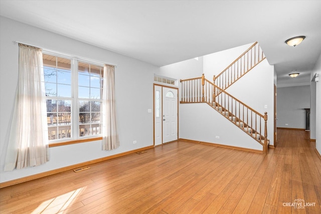 entryway with hardwood / wood-style floors, stairway, visible vents, and baseboards