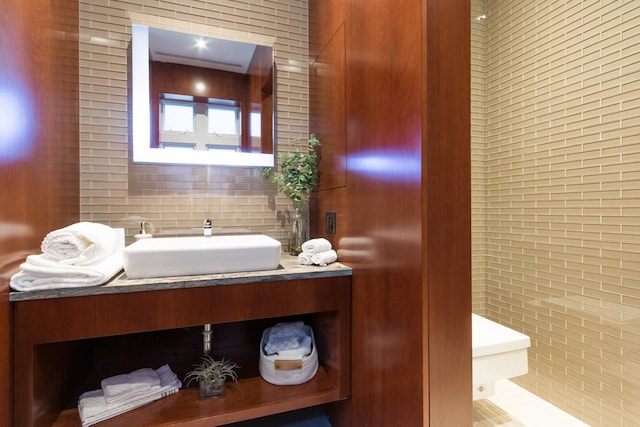 bathroom with tasteful backsplash, vanity, tile walls, and toilet