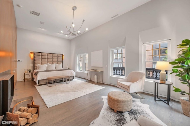 bedroom with an inviting chandelier, a towering ceiling, and wood-type flooring