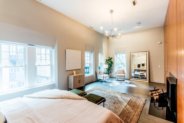 bedroom featuring a high ceiling, wood-type flooring, and a chandelier