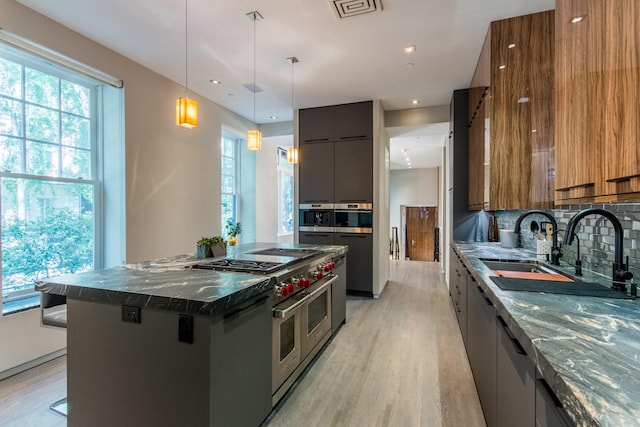 kitchen with appliances with stainless steel finishes, a kitchen breakfast bar, a center island, decorative light fixtures, and dark stone counters