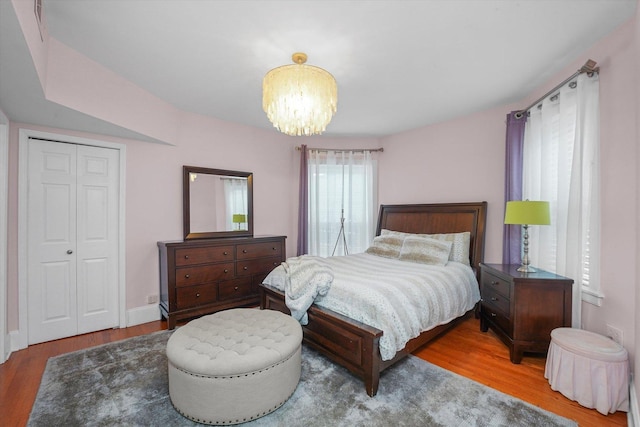 bedroom featuring hardwood / wood-style floors, a notable chandelier, and a closet