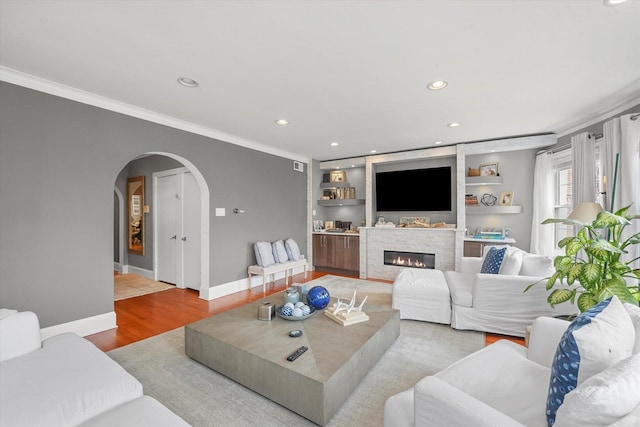 living room with crown molding, light hardwood / wood-style flooring, and built in shelves