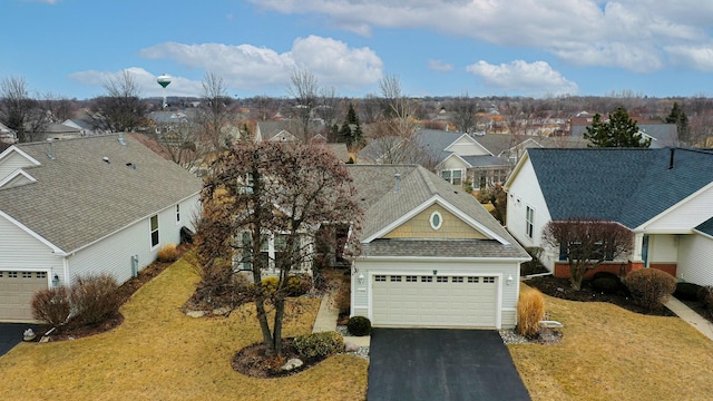 exterior space featuring driveway, a front lawn, a shingled roof, and a residential view