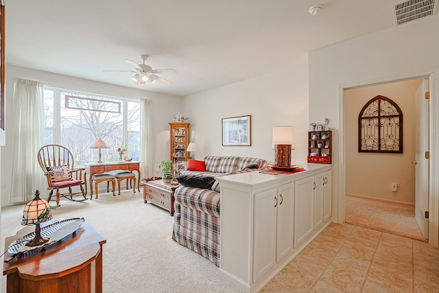 living area featuring a ceiling fan, visible vents, and light carpet