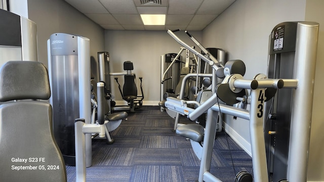 workout area featuring dark colored carpet and a drop ceiling