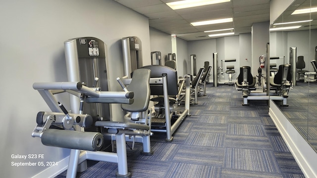 gym featuring a drop ceiling and dark carpet