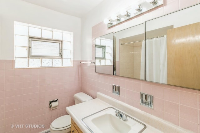 bathroom with vanity, tile walls, toilet, and walk in shower