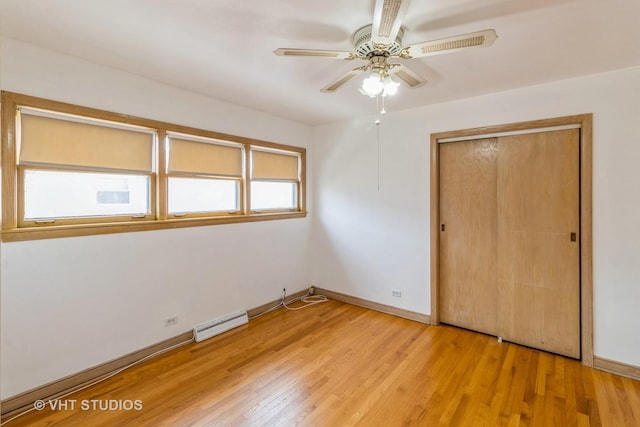 unfurnished bedroom with a baseboard heating unit, a closet, ceiling fan, and light wood-type flooring