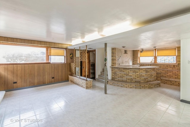 unfurnished living room with brick wall and wood walls