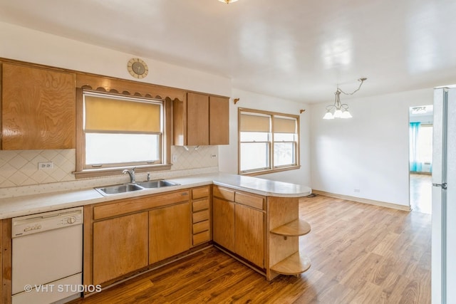 kitchen with sink, decorative light fixtures, dark hardwood / wood-style floors, kitchen peninsula, and white appliances