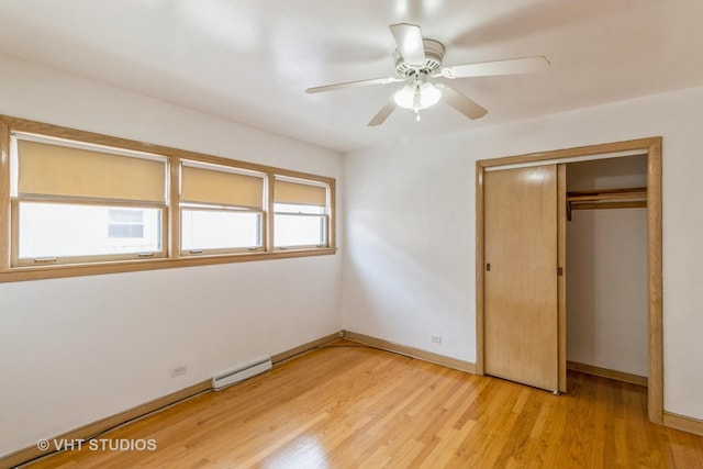 unfurnished bedroom featuring ceiling fan, a baseboard heating unit, a closet, and light wood-type flooring