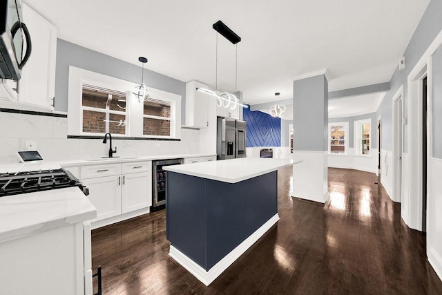 kitchen with pendant lighting, sink, stainless steel fridge, white cabinets, and beverage cooler